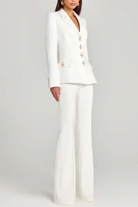 Detail of white women's blazer suit featuring unique rose gold cross-shaped buttons