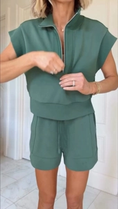 Detail of dark green two-piece set featuring half-zip sleeveless hoodie and drawstring shorts