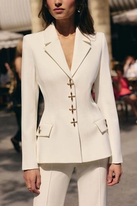 Detail of four golden cross buttons on a slim white blazer and matching trousers
