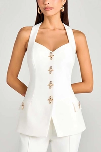 Detail of white halter vest featuring golden cross buttons and tailored waist pockets