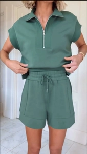 Detail of dark green two-piece lounge set featuring a half-zip short sleeve top and shorts