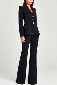 Detail of slim-fit black blazer set featuring ornate golden cross-shaped buttons on fabric