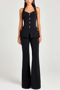 Detail of a chic black halter vest with gold cross buttons and matching trousers