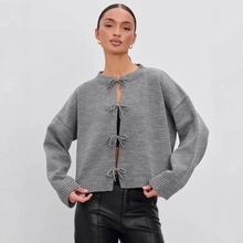 Close-up of grey long-sleeve knit cardigan featuring delicate bow-tie closures on the front