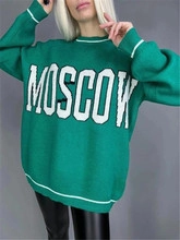 Detail of green oversized knit sweater featuring white MOSCOW letter print and striped cuffs