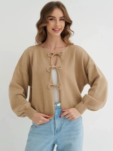 Detailed knit texture of camel cardigan with three front bow ties and ribbing