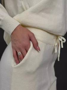 Détail de la texture de l'ensemble en tricot écru et bague dorée avec diamant carré