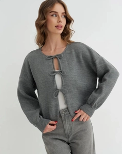 Detail of grey knitted cardigan with three stylish bow tie closures and soft texture