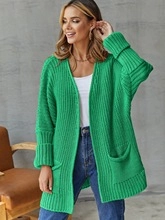 Detail of bright green oversized cardigan featuring vertical ribbed texture and deep pockets