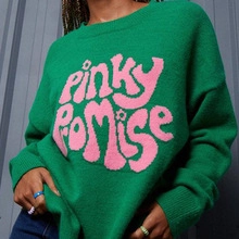 Detail of pink embroidered lettering and ribbed knit texture on green cardigan