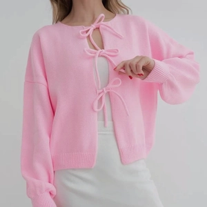 Close-up of pink knit cardigan with bow tie closures and stylish lantern sleeves