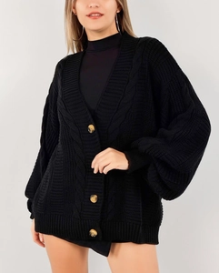 Vue détaillée du tricot à grosses torsades et des boutons ambrés sur ce cardigan noir