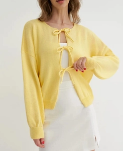 Detail of yellow knit cardigan featuring front bow ties and soft lantern sleeves