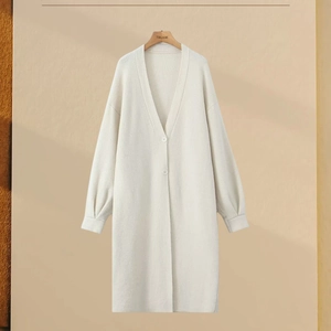 Close-up of ribbed knit cuffs and buttons on a cream long-sleeved oversized cardigan