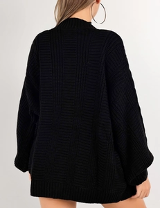Détail de la veste en maille noire surdimensionnée montrant la texture épaisse et côtelée