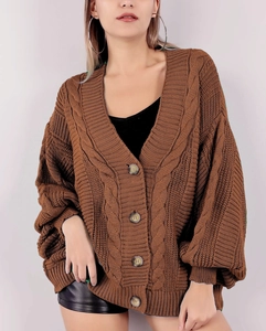 Gros plan sur un cardigan marron en grosse maille torsadée avec boutons en bois