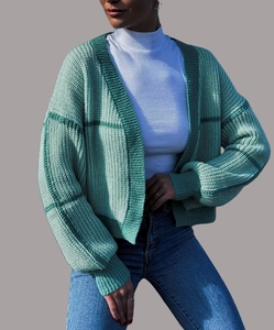 Close-up of light green knit cardigan with dark green stripes and ribbed cuffs on a model