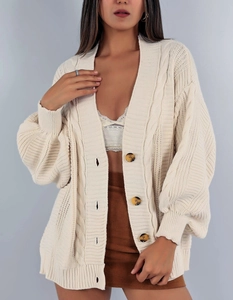 Gros plan du cardigan en maille crème montrant la texture torsadée et les boutons marron