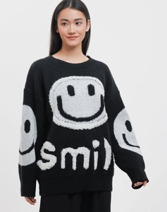 Detail of white jacquard smiley face and smile text on a black oversized knit sweater
