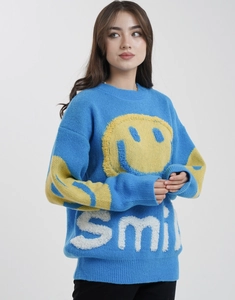 Detail of blue knit sweater with yellow fuzzy smiley face and white smile lettering