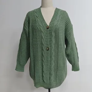 Détail macro du cardigan vert en grosse maille torsadée avec col en V et boutons