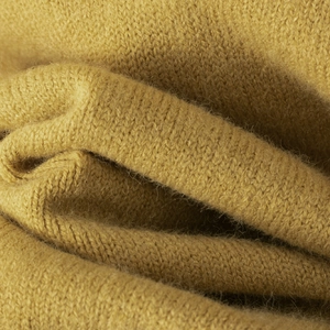 Détail macro du tricot jaune moutarde montrant la texture douce et les fibres denses