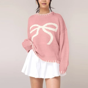 Close-up of pink knit sweater with white bow pattern and contrast stitching details