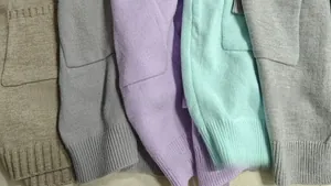 Detail view of five different colors of knited cardigans with ribbed cuffs and pockets