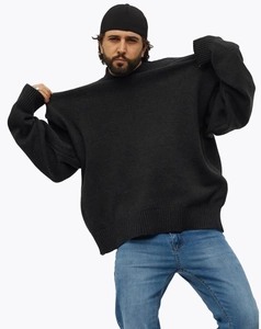 Détail du pull en maille noire oversize montrant la texture épaisse et le col côtelé