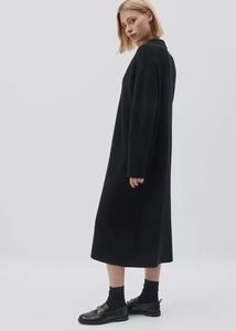 Detail of elegant long black knit dress with loafers and golden horsebit buckle