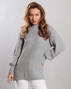 Detailed view of grey chunky knit sweater featuring ribbed cuffs and wavy textured pattern