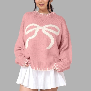Cozy pink knit sweater with white bow pattern and loose drop shoulder silhouette
