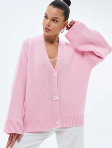 Détail d'un cardigan en maille rose clair avec texture épaisse et gros boutons ronds