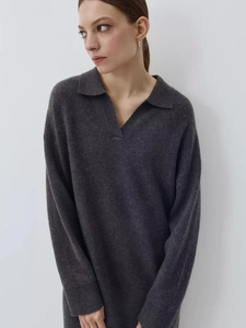 Detailed close-up of dark grey knit sweater texture with ribbed cuffs and polo collar