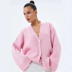 Détail du cardigan rose en maille épaisse avec col en V et finitions côtelées aux poignets