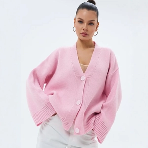 Détail de la maille épaisse et des boutons roses sur le gilet oversize avec col en V
