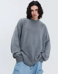 Détail de la texture en maille côtelée et du col rond sur un pull oversize gris foncé de qualité
