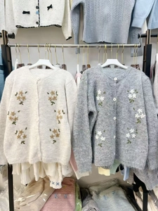 Gros plan détaillé des broderies florales et des boutons ronds sur les cardigans en maille