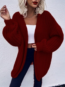 Oversized dark red chunky knit cardigan featuring cable stitch patterns and ribbed cuffs