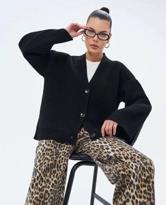 Détail d'un cardigan noir à col en V avec boutons marbrés et finitions en maille côtelée