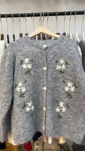 Détail du cardigan gris duveteux avec broderies florales blanches et boutons ronds