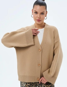 Détail d'un cardigan en maille kaki montrant le col en V et les gros boutons bruns