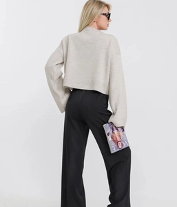 Vista posteriore di un maglione corto beige e pantaloni neri a vita alta e gamba larga