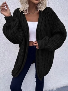 Detail of chunky knit texture and lantern sleeves on a black oversized cardigan