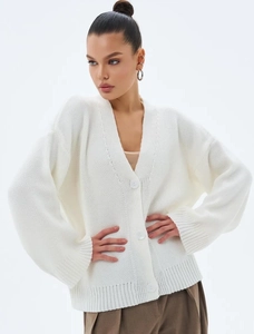 Détail d'un cardigan en grosse maille blanche avec col en V et grands boutons assortis