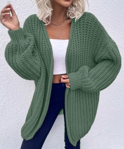 Detailed close-up of dark green oversized knit cardigan with chunky stitch texture