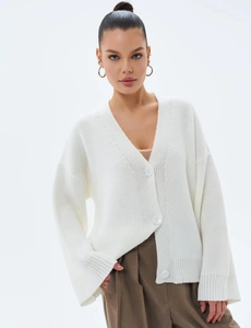 Gilet en maille blanche avec col en V, trois grands boutons et texture de bords-côtes
