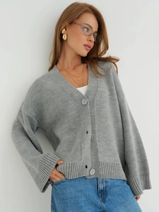 Détails du gilet en maille grise montrant le col en V, les coutures et la texture des boutons