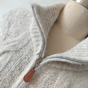 Close-up of knit sweater fabric with metal zipper and brown leather puller detail