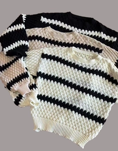 Detailed view of women's striped sweaters featuring thick textured bubble knit fabric